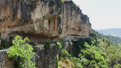 Tilt-up-aerial-shot-of-a-beautiful-sandstone-hill-covered-in-trees-and-bushes