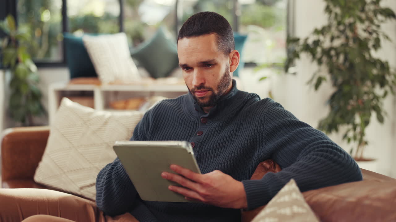 Man relaxing at home using tablet on couch