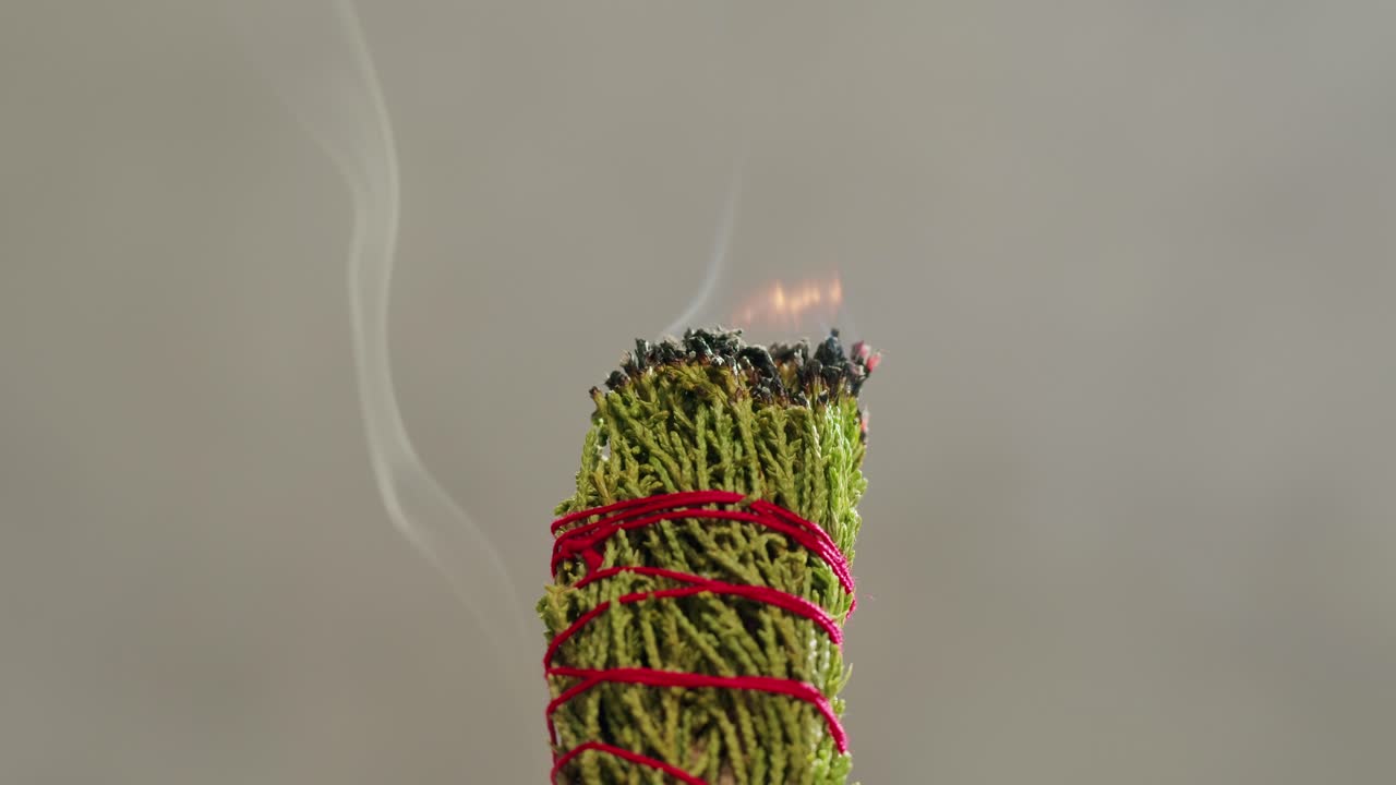 Person holding Palo Santo wood stick in hand, aromatic Palo Santo burning on black background, smoke spreading around, slow motion video clip, high quality 4k close up footage. High quality 4k footage