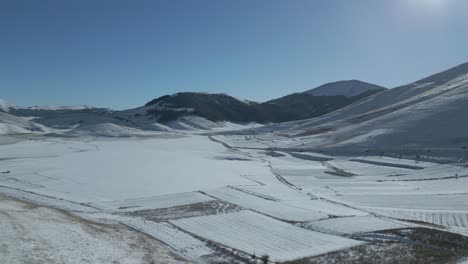 a drone footage over castelluccio - italy during winter period with snow