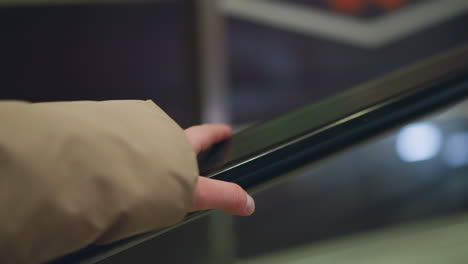 close-up of a hand gripping a moving rail, with a blurred background that conveys motion. focuses on the texture of the rail and the natural movement of the hand