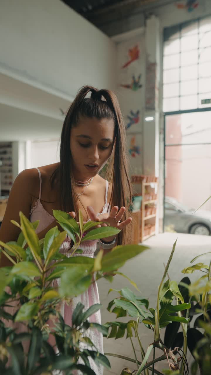 A woman tending to indoor plants in a bright, naturally lit retail space
