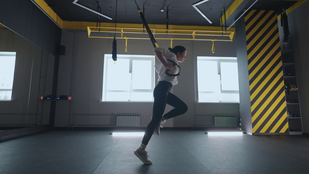 체육관에서 트랙스 운동을 하는 스포츠 여성. 체육관에서 피트니스 스트램으로 훈련하는 여성. 근육 스링이나 서스펜션 스트램을 운동하는 아름다운 여성.