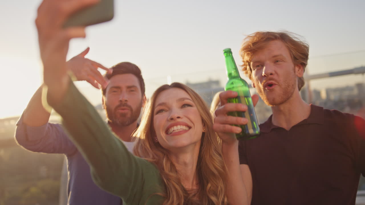 celebrando a la gente saludando a la cámara del teléfono inteligente divirtiéndose en el techo de cerca.