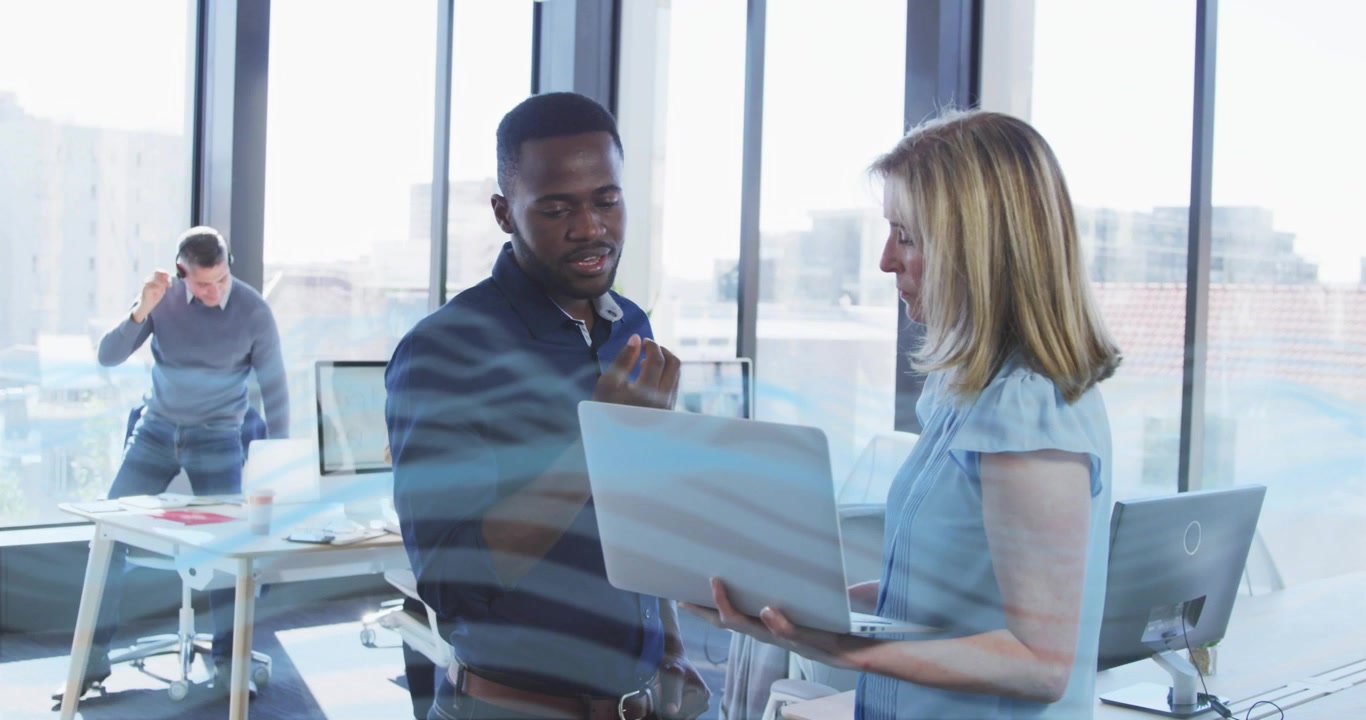 businesswoman approaching colleague and presenting data on laptop while animated charts for review