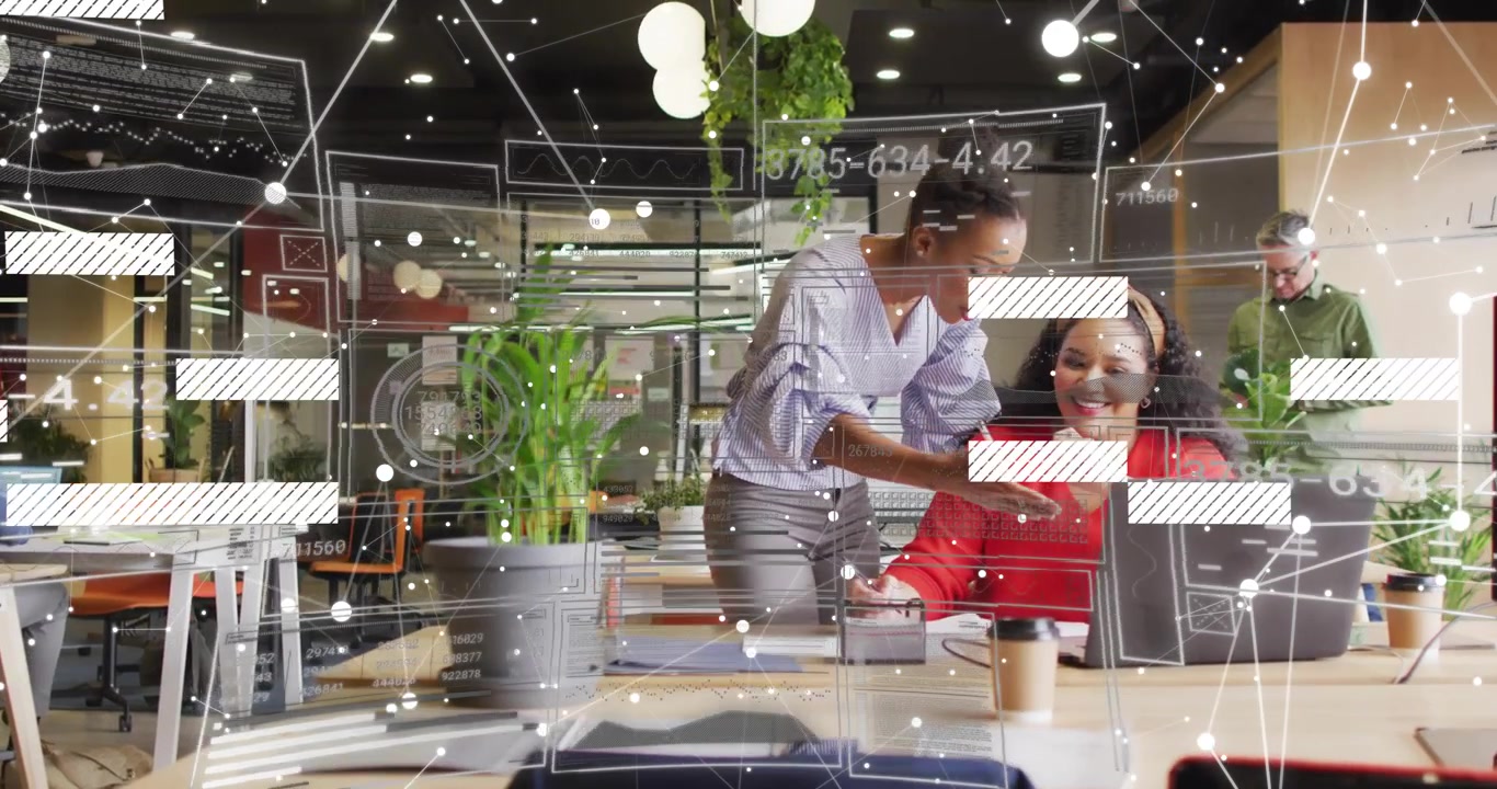 Femme assise tapant sur un ordinateur portable, un collègue pointant un smartphone et expliquant une superposition de données dans un pôle technologique.