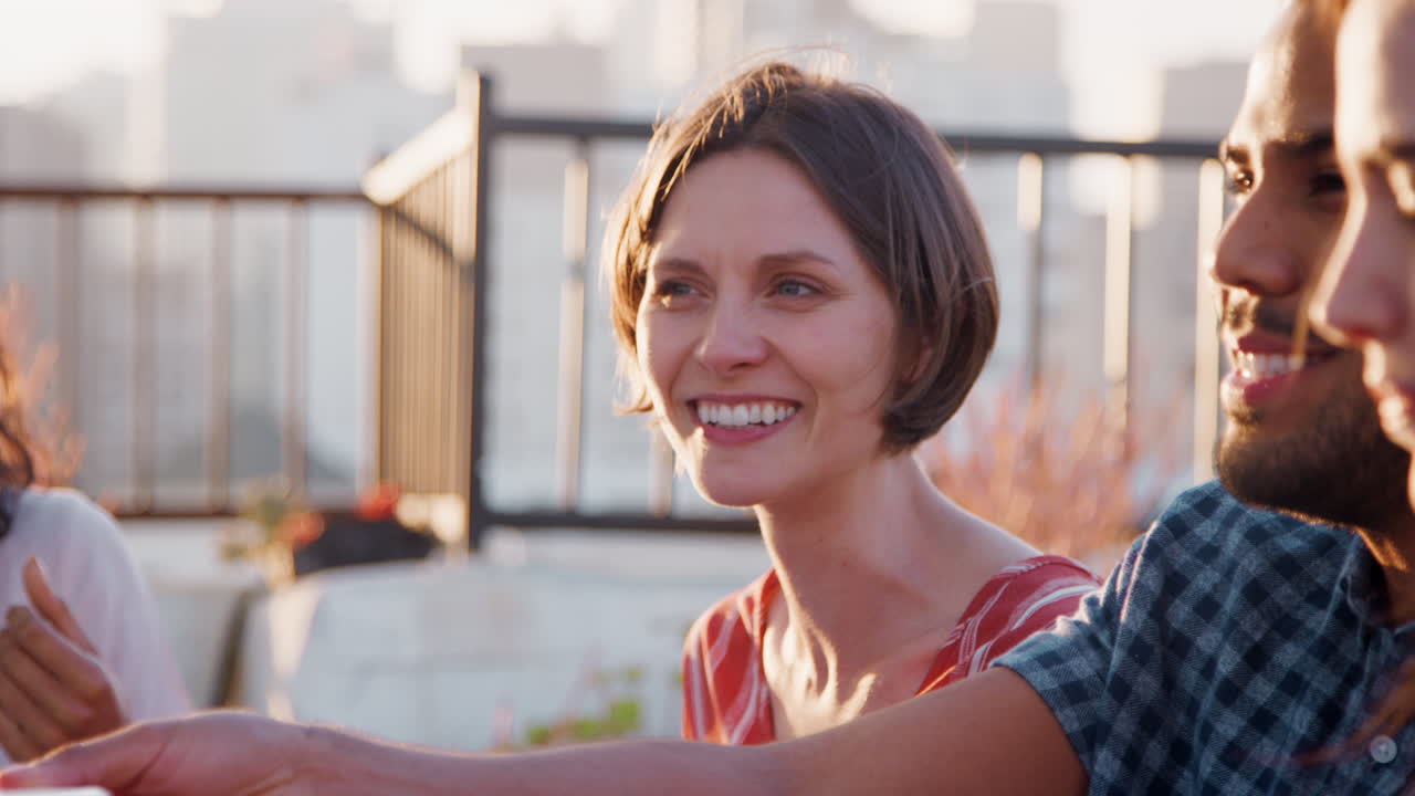 Freunde versammeln sich auf der Dachterrasse zum Essen mit der Skyline der Stadt im Hintergrund