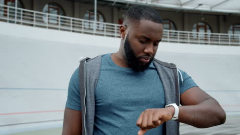 man using smart watch on racetrack