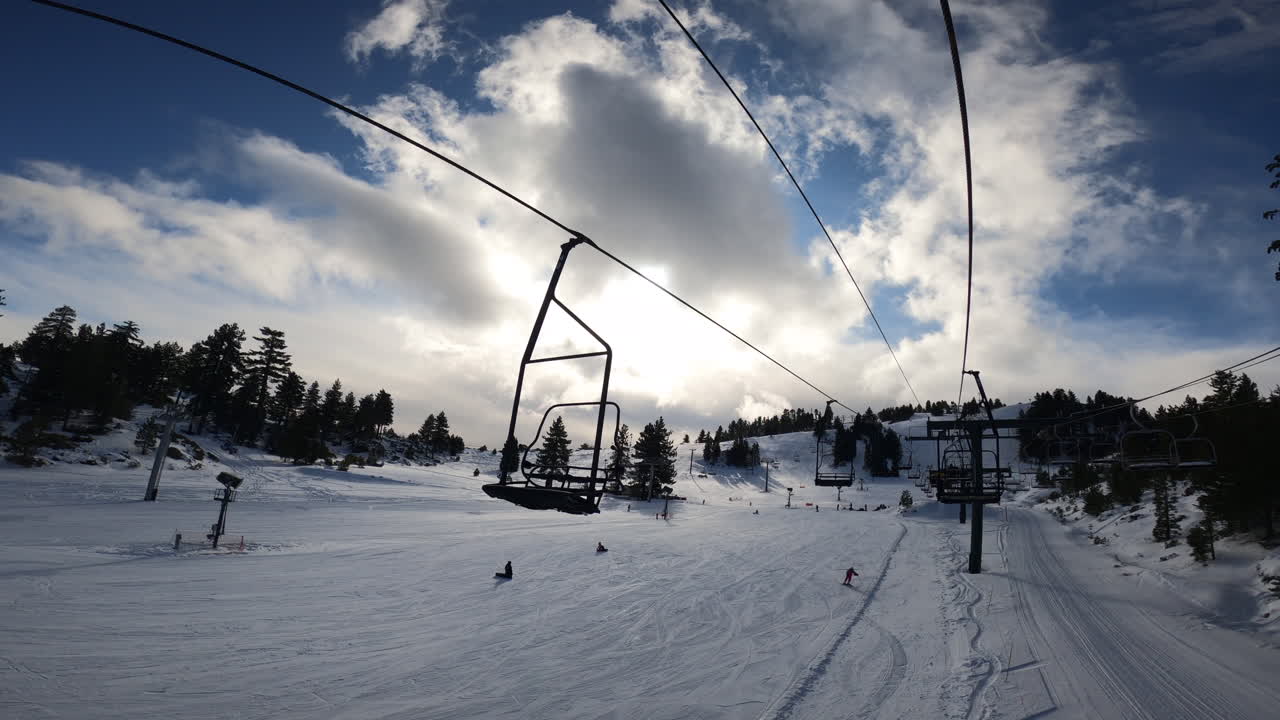 POV: Salita su seggiovia in paesaggio innevato con cielo blu nuvoloso, MOVIMENTO LENTO