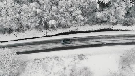 Drone-footage-of-car-driving-in-the-winter-forest-road