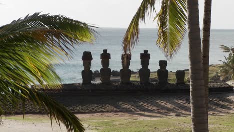 Osterinsel-Statuen-Mit-Dem-Meer-Im-Hintergrund-Und-Palmen-Winken