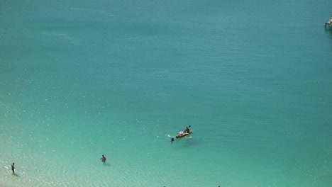 Beachgoers-enjoying-a-sunny-day-in-shallow-turquoise-tropical-beach,-aerial-view