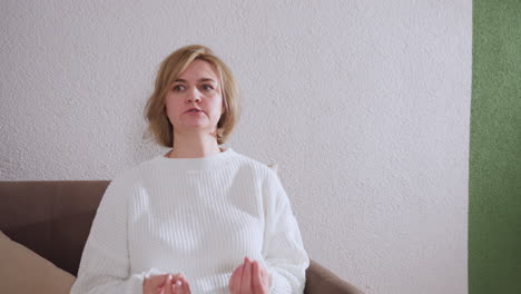 zoomed capture of individual in need demonstrating with hands while speaking to attentive therapist taking notes in calm counseling space with green accent wall brown sofa clock pen pack visible