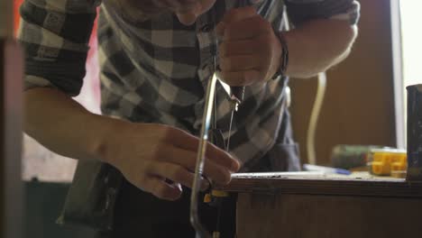 Man-using-coping-saw-to-make-anchor-bracelet