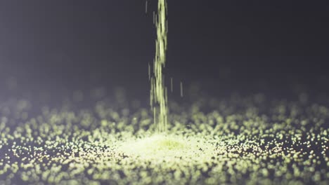 video of close up of green sand grains pouring into heap and copy space on black background