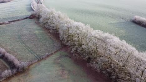 Aerial-view-of-a-road-going-through-the-frozen-farm-land-in-the-belgian-hills-in-southern-Belgium,