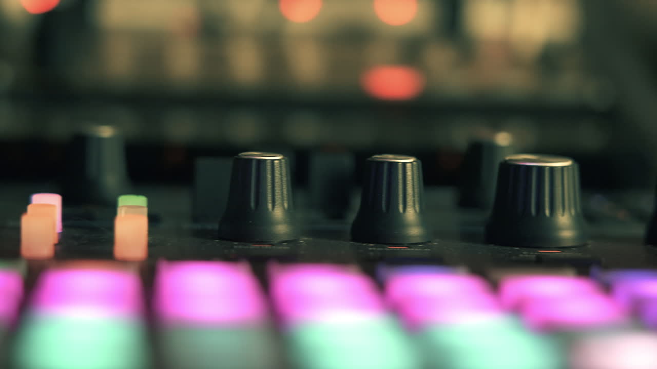 Primo piano di mixer audio con pulsanti e manopole illuminati