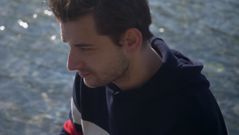 Close-up-of-a-the-hands-of-a-handsome-young-man-sitting-on-the-bank-of-a-canal-in-Amsterdam-typing-on-the-notebook