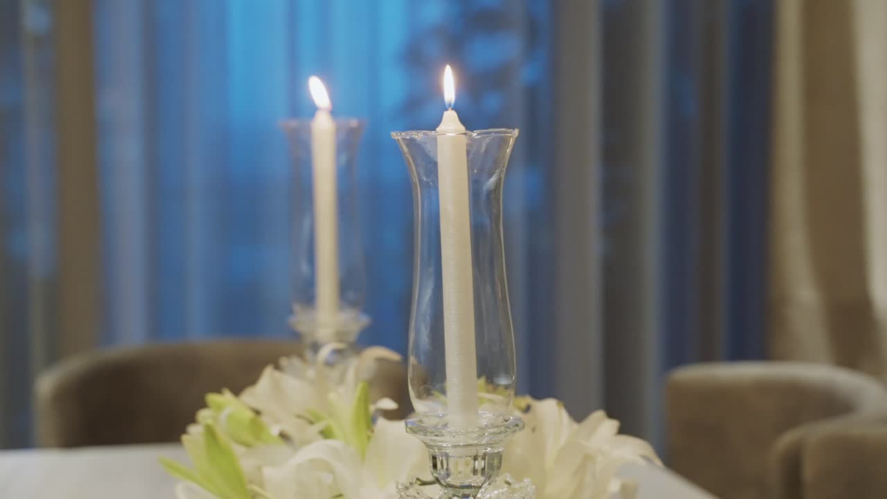 velas blancas encendidas en candelabros de vidrio altos en la mesa de comedor
