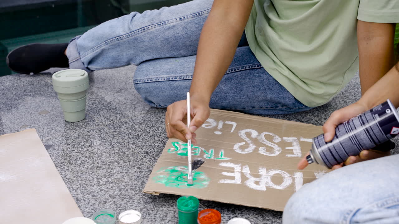 mujer pintando tablero con pincel y su amiga está rociando