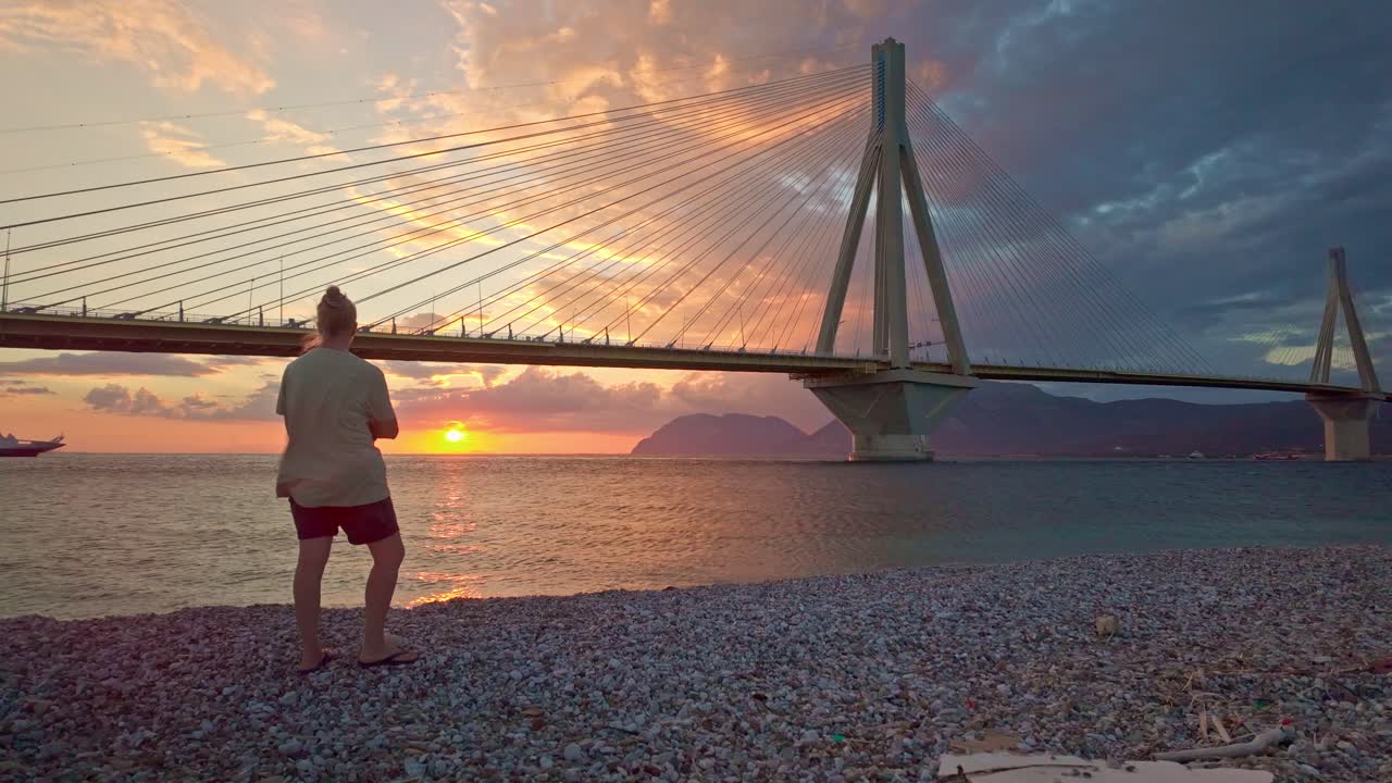 Woman on beach gazing thoughtfully fiery sunset Bay of Corinth horizon