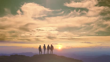 the four people standing on a mountain on a beautiful sunrise background