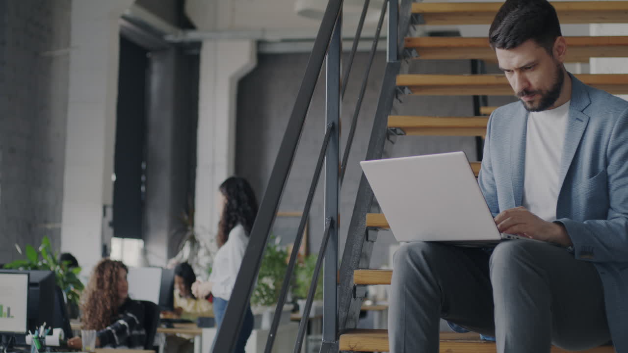 Uomo d'affari che lavora su un laptop sulle scale dell'ufficio