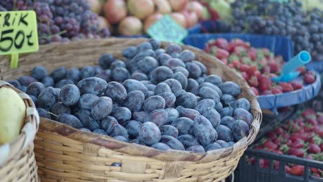 fresh plums, strawberries, and grapes at a farmers market