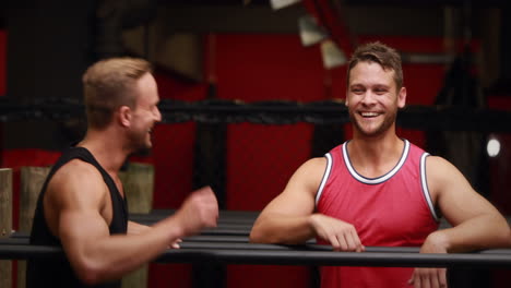 trainer helping client to l hang in crossfit gym