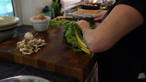 a chef chops greens on a cutting board