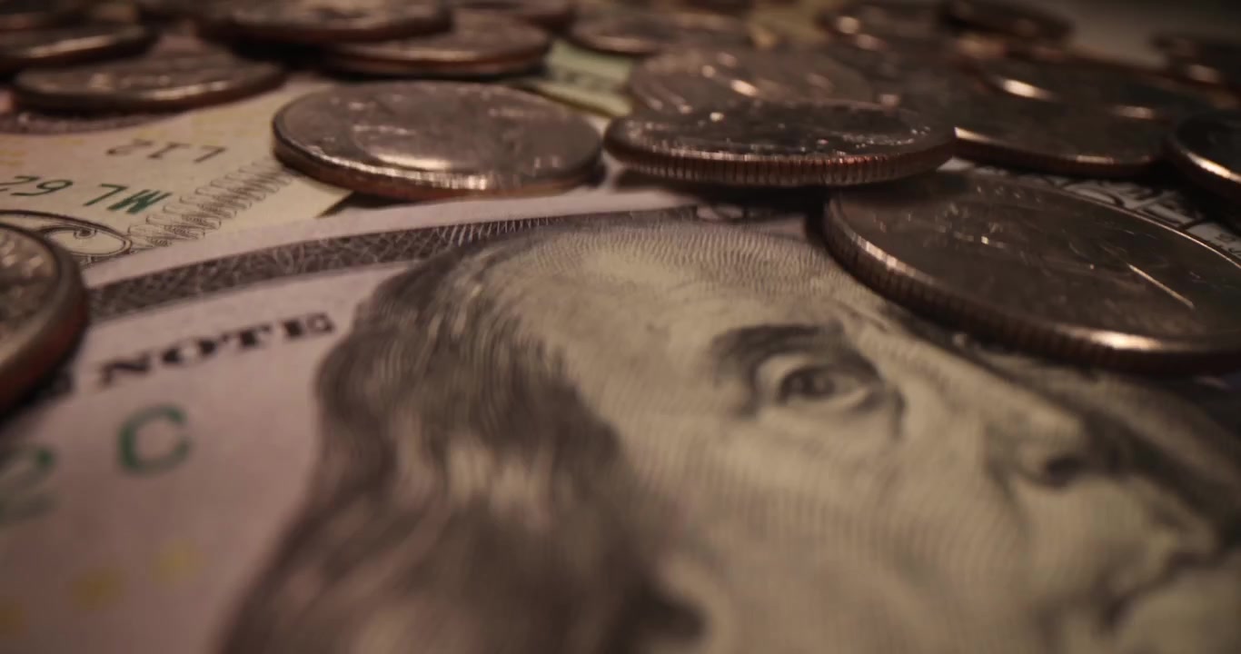 Banconote da un dollaro con Benjamin Franklin e numerose monete che cadono