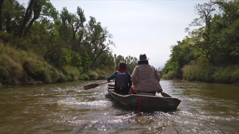 aerial low-tracking shot of a family kayaking down a river