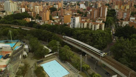 aerial view of medellin metro train with buildings in background