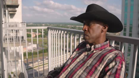 black man with cowboy hat sleeping in chair on balcony