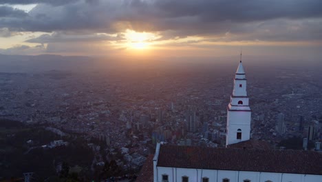 Drone-shot-of-Monserrate-church-overlooking-the-city-of-Bogota,-Colombia-at-sunset