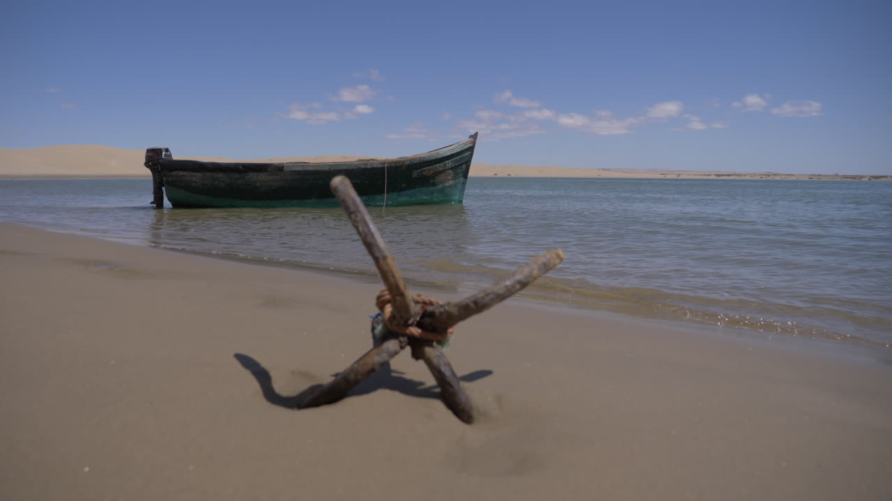 un pequeño barco ha anclado en la playa en el desierto del sahara.