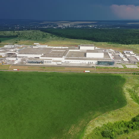 aerial view on the large territory of industrial structure on the natural landscape in summer. panoramic view of green fields and manufacturing buildings outdoors. camera moves right.