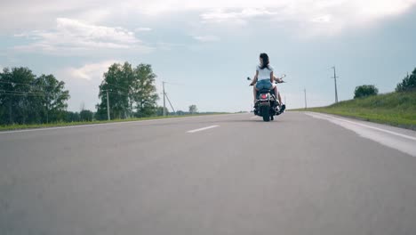 Disparo-De-ángulo-Bajo-Un-Hombre-Y-Una-Mujer-Jóvenes-Viajan-En-Motocicleta-Negra