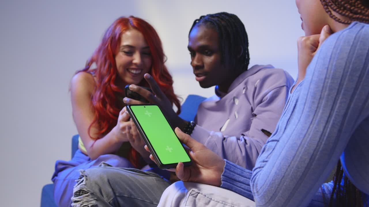 Close Up Of Woman With Green Screen Mobile Phone Sitting With Gen Z Friends Talking And Sharing Posts 1