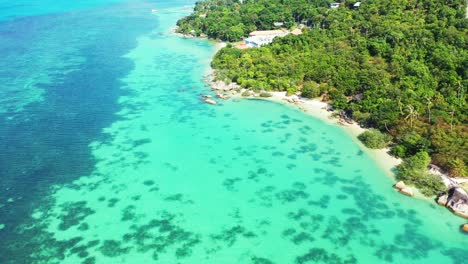 Beautiful-pattern-of-sea-bottom-with-coral-reefs-thriving-on-white-sand-under-calm-clear-water-of-turquoise-lagoon-of-Thai-tropical-island