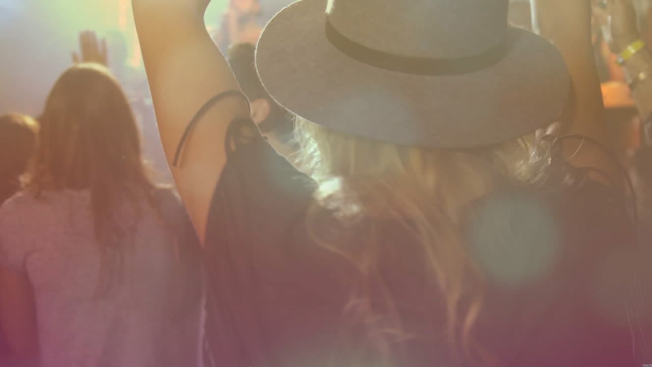 Woman in brimmed hat raising arms, singing on music beat at concert, animated flares tracking hands