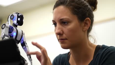 engaging interaction between human and robot: a close-up of a woman collaborating with a small humanoid robot in a learning environment