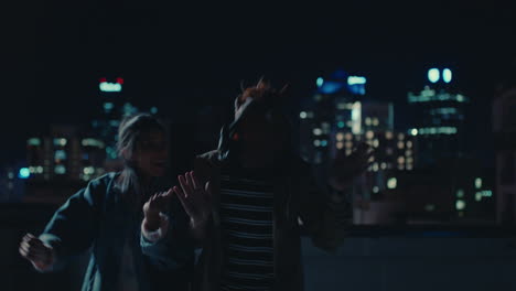 funny man wearing horse mask dancing with friends on rooftop having fun performing silly dance moves celebrating weekend together in urban city skyline