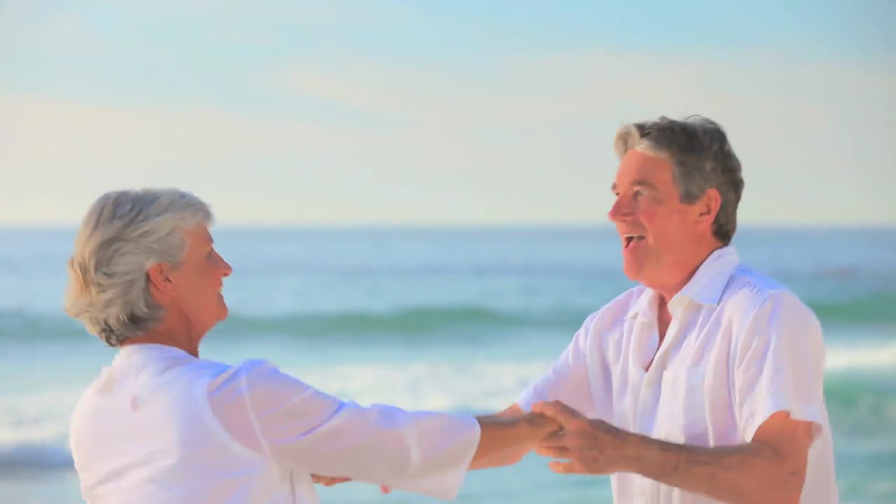 성숙한 커플이 바다 가장자리에서 춤을 춘다