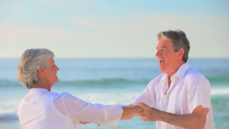 mature couple dancing at the edge of the sea