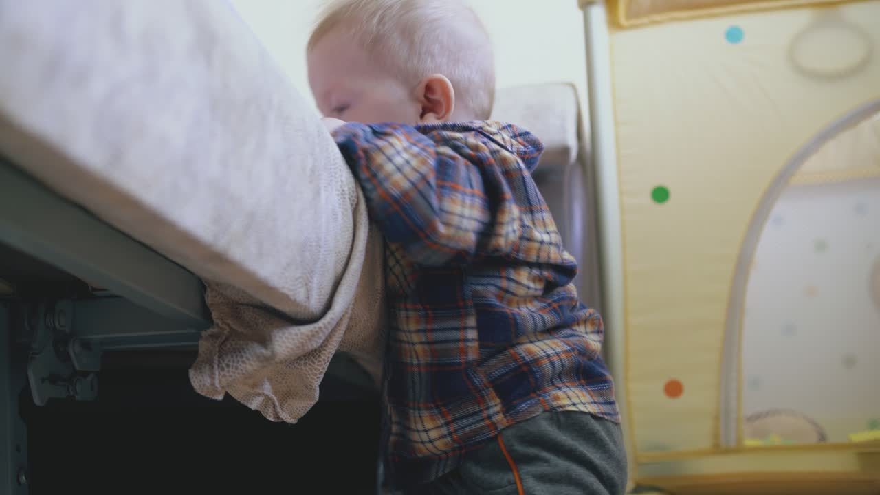 little baby in shirt and pants plays at large soft bed