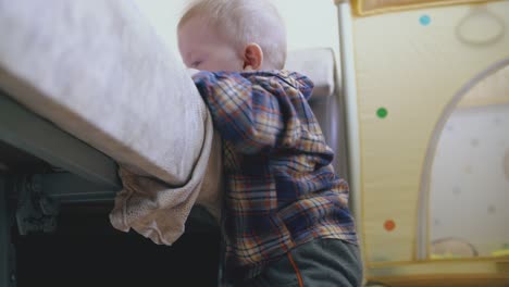 little baby in shirt and pants plays at large soft bed