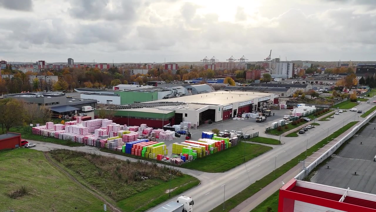 Ulkona oleva eristemateriaalin varastoalue värikkäine pinoineen teollisuusrakennusten lähellä