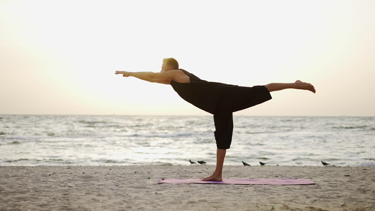 un joven está haciendo yoga en una alfombra deportiva, de pie en una pierna durante el amanecer del hijo. haciendo un ejercicio específico. meditación