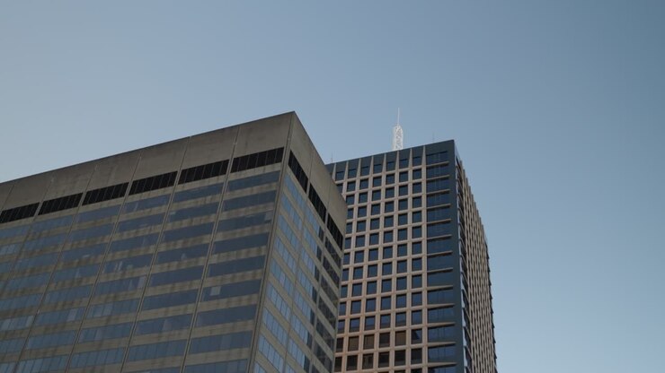 Dois edifícios de escritórios modernos em Sydney erguendo-se em um céu azul claro.